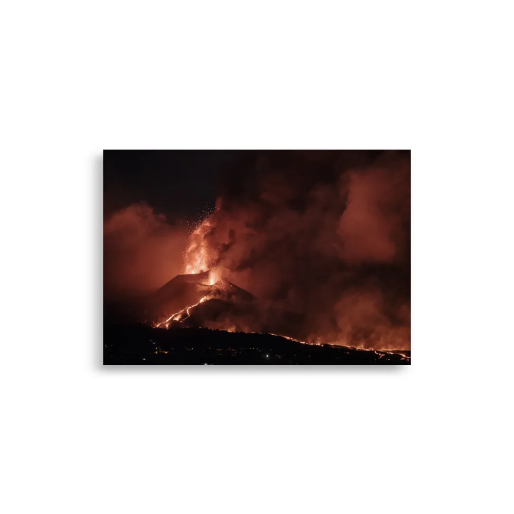 Un volcán entra en erupción por la noche, arrojando lava de color naranja brillante que recuerda a las vívidas imágenes del "Póster volcán 2021 La Palma noche" de Volcanica Productions, y emitiendo densas nubes de humo hacia el cielo oscuro. La lava fundida fluye por sus laderas, iluminando un paisaje que refleja la esencia de Paisajes Canarios.