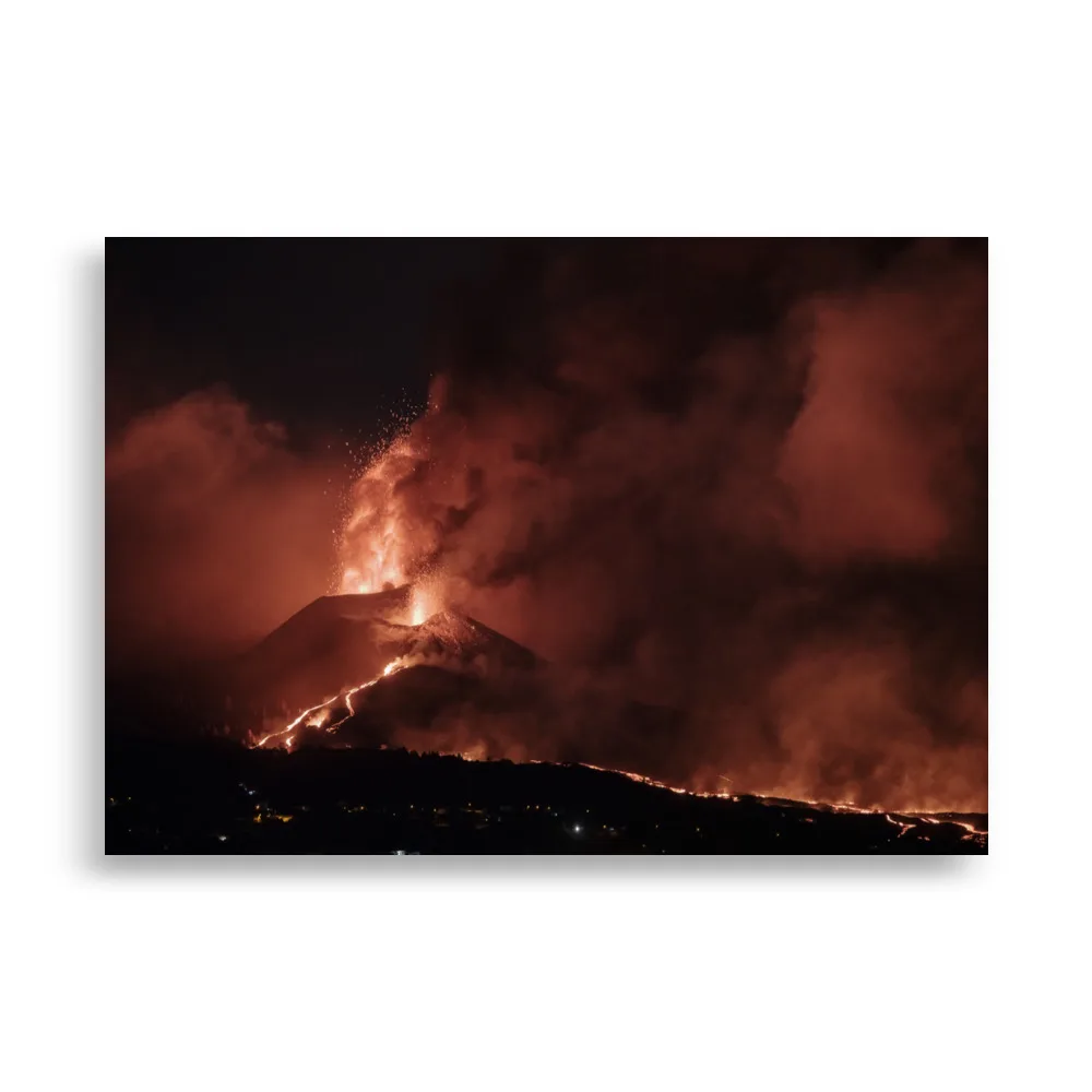 Una imagen nocturna de un volcán en erupción, con lava de color naranja brillante fluyendo por sus laderas y explosiones ardientes que iluminan el cielo oscuro, todo envuelto en nubes de ceniza y humo, ideal para aquellos que buscan capturar impresionantes paisajes canarios con el "Póster volcán 2021 La Palma noche".
