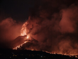 El Póster volcán 2021 La Palma noche captura una escena dramática de un paisaje oscuro en La Palma, donde un volcán entra en erupción, arrojando cenizas y lava al cielo nocturno. La lava brillante fluye por las laderas de las montañas, formando estelas de fuego contra el fondo oscuro, mientras que el humo denso se suma a este espectáculo de Paisajes Canarios que recuerda al Arte Decorativo.