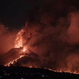 El Póster volcán 2021 La Palma noche captura una escena dramática de un paisaje oscuro en La Palma, donde un volcán entra en erupción, arrojando cenizas y lava al cielo nocturno. La lava brillante fluye por las laderas de las montañas, formando estelas de fuego contra el fondo oscuro, mientras que el humo denso se suma a este espectáculo de Paisajes Canarios que recuerda al Arte Decorativo.