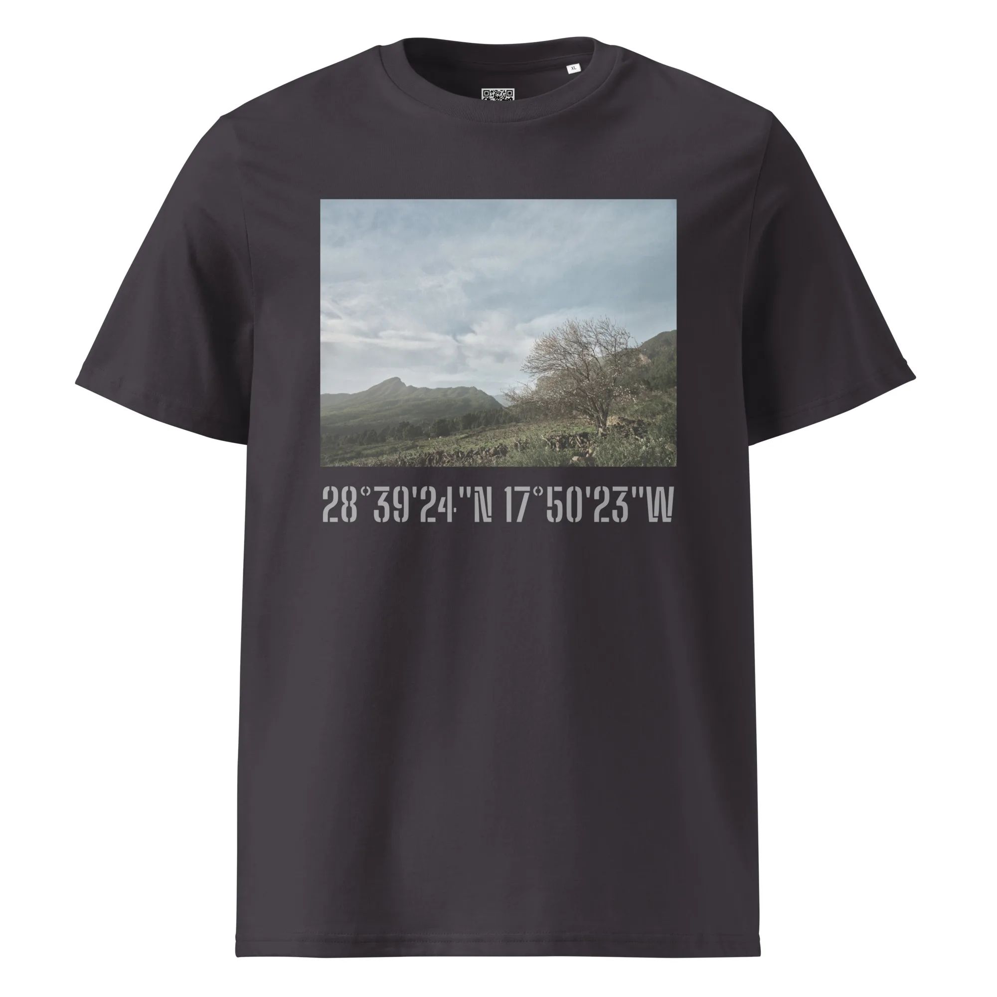 La camiseta unisex Camino Virgen del Pino es una camiseta negra que muestra un pintoresco paisaje de montaña con un cielo nublado como fondo. Debajo de la imagen se encuentran las coordenadas 28°3924N 17°5023W, marcadas por Volcanica Productions, que encarnan el espíritu de Paisajes Canarios de La Palma.