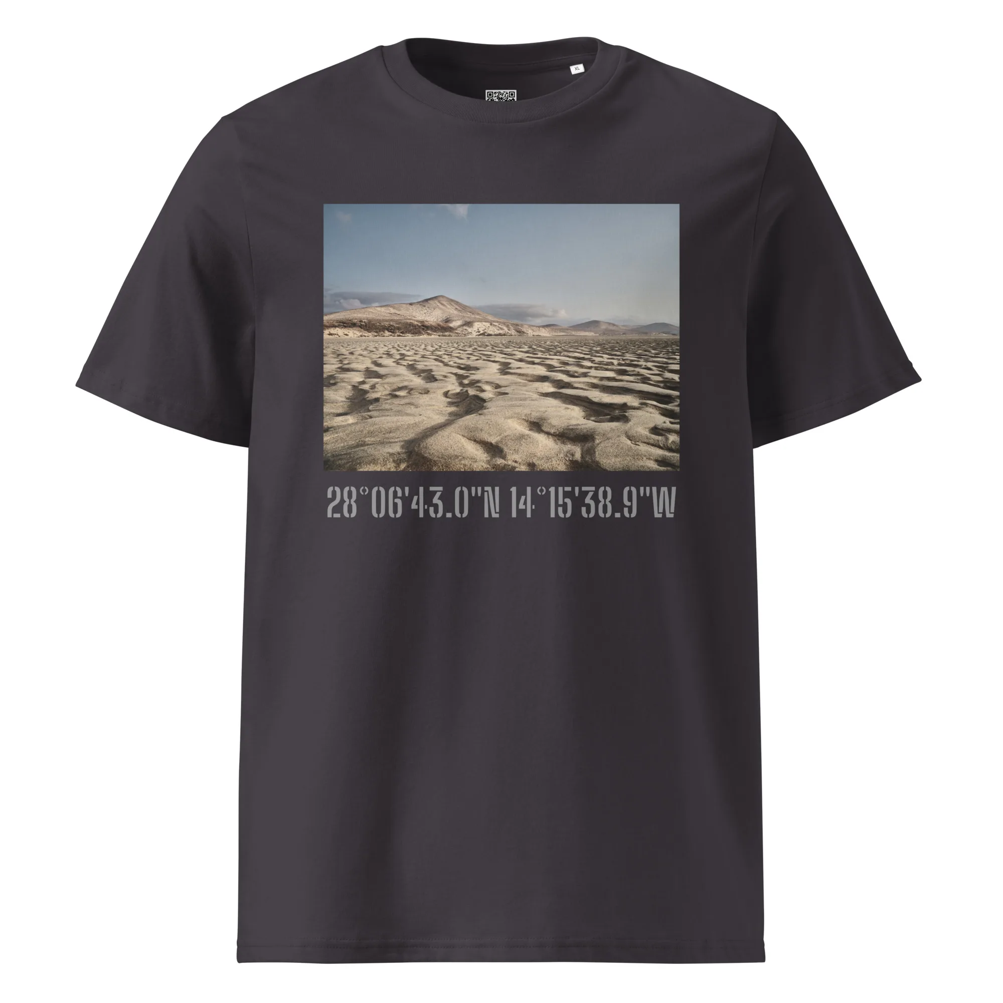 Camiseta unisex Sotavento en color negro con una fotografía de un paisaje desértico que muestra dunas y montañas, capturada por Volcanica Productions. Debajo de la imagen, las coordenadas 28°0643.0N 14°1538.9W están impresas en blanco, exhibiendo los impresionantes Paisajes Canarios con detalle exquisito.