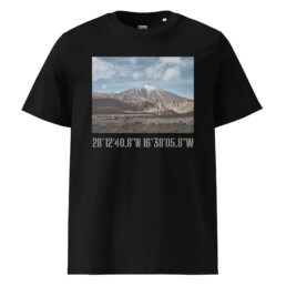 Camiseta unisex Teide Nevado en color negro, con un paisaje de montaña y cielo nublado de Paisajes Canarios. Debajo de la imagen, el texto en blanco con las coordenadas 28°1240.8N 16°3805.8W realza el diseño con un elemento decorativo.