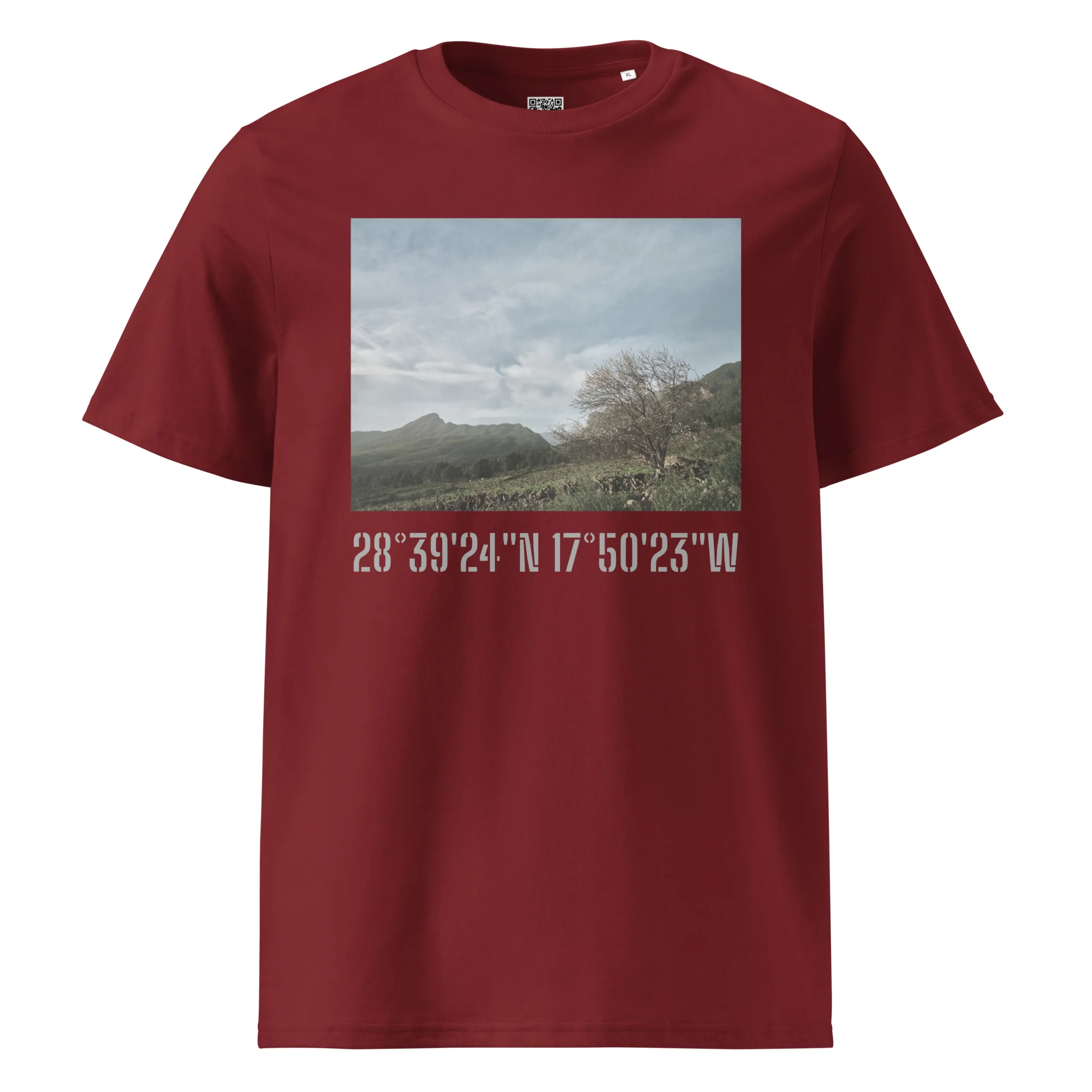 La camiseta unisex Camino Virgen del Pino es una camiseta de color rojo oscuro adornada con una imagen impresa de un paisaje que muestra montañas y árboles bajo un cielo nublado. Debajo de la imagen, las coordenadas geográficas 28°39'24"N 17°50'23"W se muestran de forma destacada en negrita y en gris claro. Este artículo de Arte Decorativo encapsula con elegancia el espíritu de Paisajes Canarios.