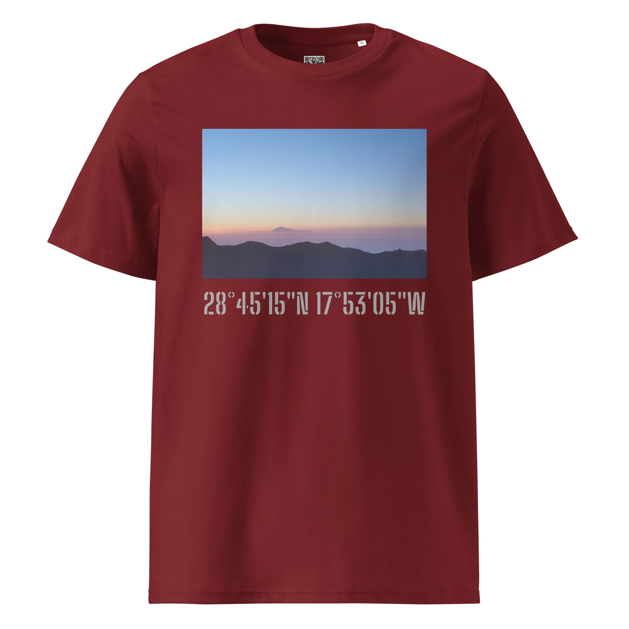 Una camiseta en color granate presenta una imagen rectangular de un paisaje de montaña de La Palma al amanecer o al atardecer, sobre un cielo despejado y degradado. Debajo de la imagen, las coordenadas blancas 28°45′15″N 17°53′05″W resaltan Paisajes Canarios. Este producto, llamado "Camiseta unisex Amanecer desde el Roque de los Muchachos", ya está disponible en nuestra Tienda Online.