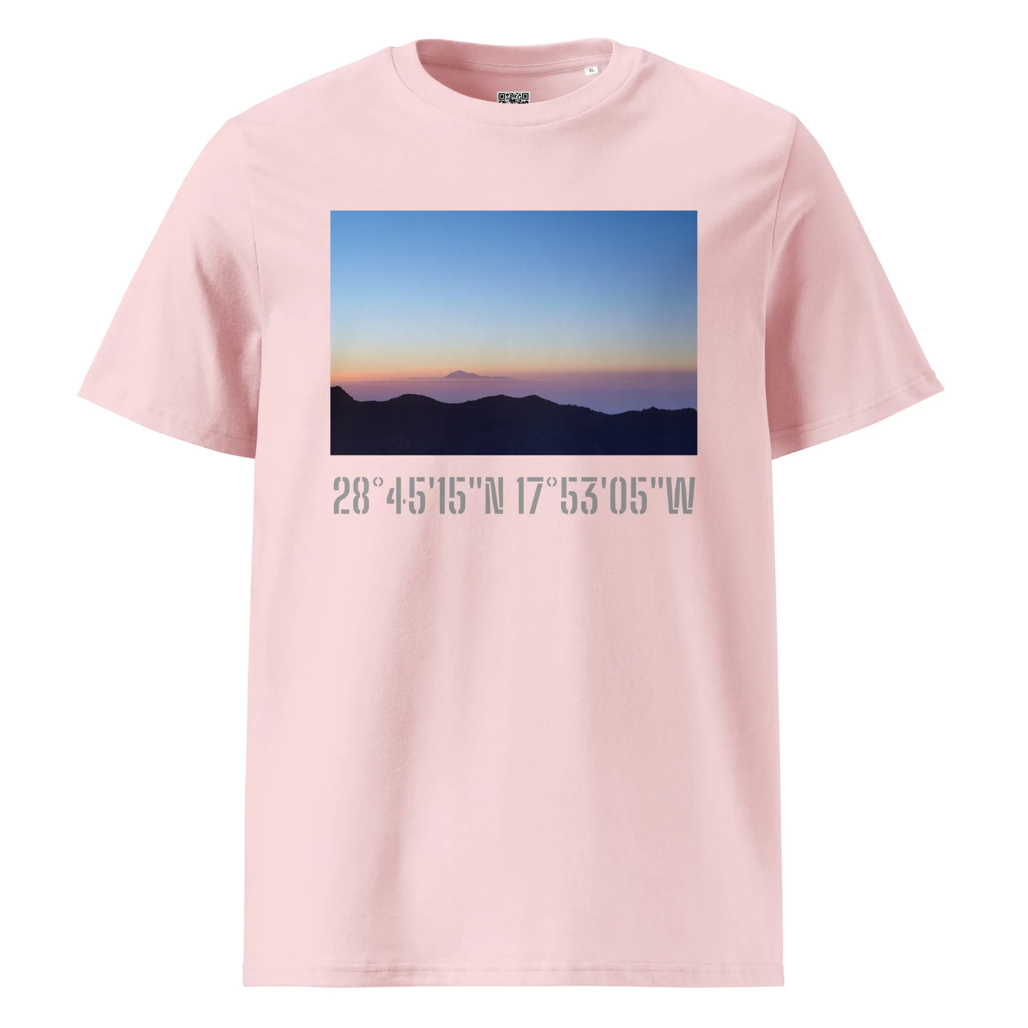La camiseta unisex "Amanecer desde el Roque de los Muchachos" de Volcanica Productions es una camiseta rosa que muestra un impresionante atardecer o amanecer sobre montañas lejanas. Debajo de la imagen, están impresas las coordenadas geográficas 28°4515N 17°5305W, que resaltan los impresionantes paisajes de La Palma en la serie Paisajes Canarios.
