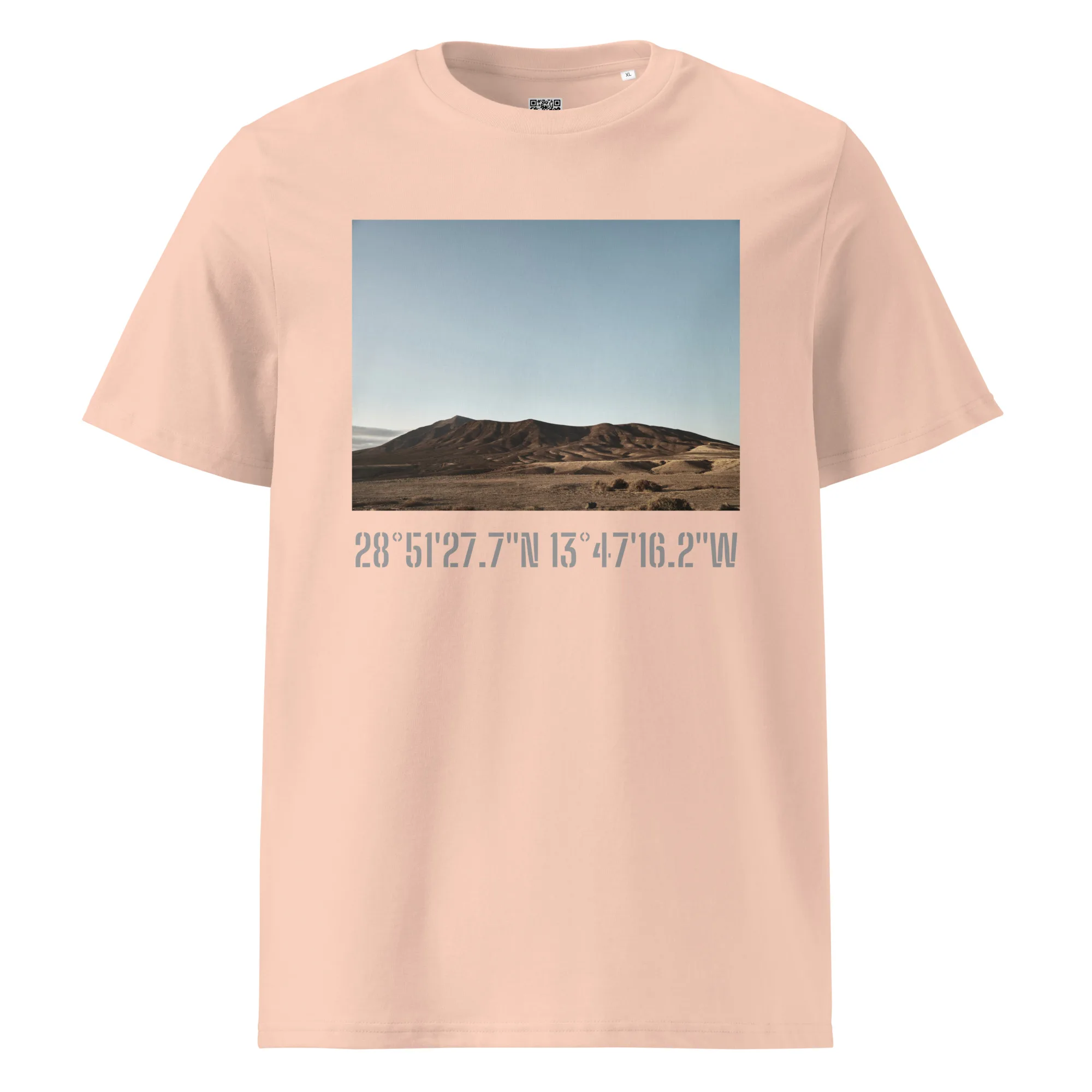 Experimenta la moda moderna con la "Camiseta unisex Los Ajaches" en color beige, que presenta un paisaje desértico de colinas onduladas bajo un cielo azul. Debajo de la obra de arte, encontrarás las coordenadas 28° 51' 27.7"N 13° 47' 16.2"W elegantemente impresas, que encapsulan el espíritu de Paisajes Canarios.