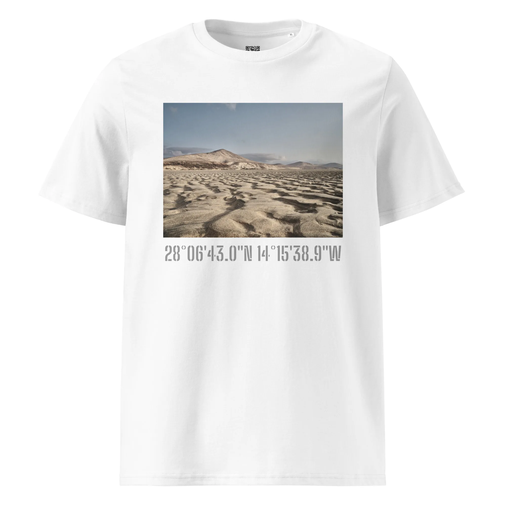 La camiseta unisex Sotavento presenta un estampado de paisaje desértico con dunas de arena y colinas rocosas que recuerda a Paisajes Canarios. Las coordenadas 28°0643.0N 14°1538.9W realzan el diseño, añadiendo un toque geográfico.