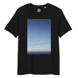 La camiseta unisex Teide y Paloma presenta un diseño minimalista con un estampado vertical de un pájaro solitario en un alambre, con el tranquilo telón de fondo del Teide y el lejano horizonte del océano.